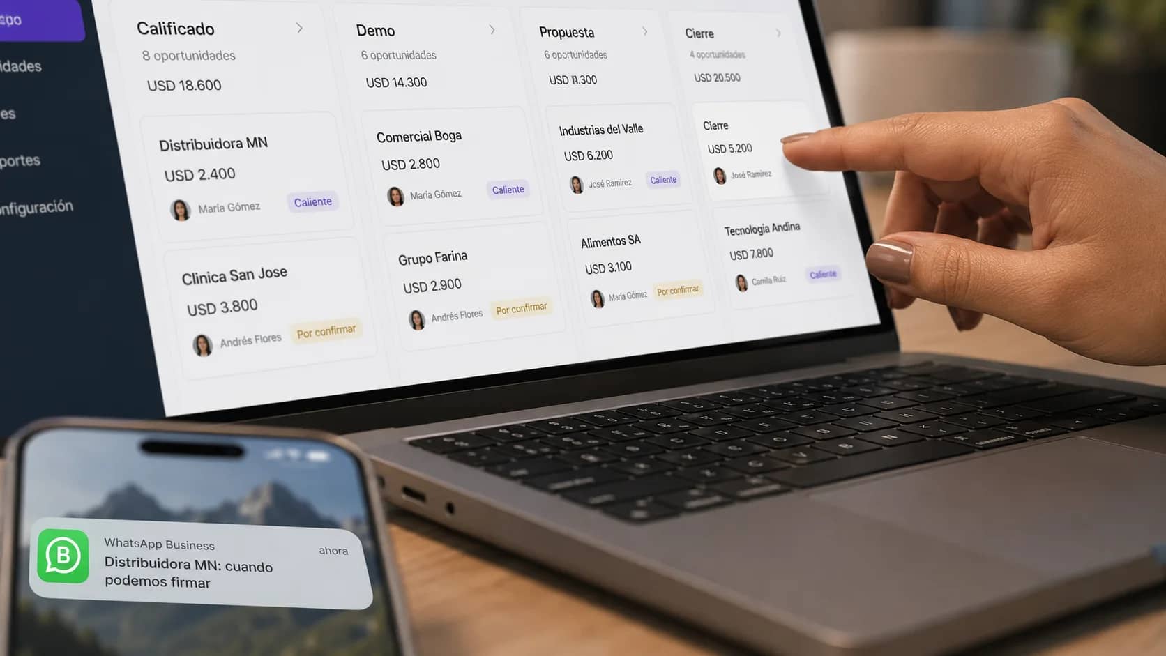 Close-up de un dashboard CRM con pipeline visual de ventas y una mano interactuando con la pantalla mientras un iPhone muestra una notificación de WhatsApp Business