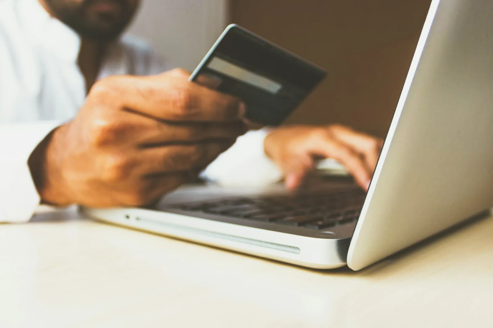 Persona comprando en línea con tarjeta y laptop mientras un asistente de IA compara opciones