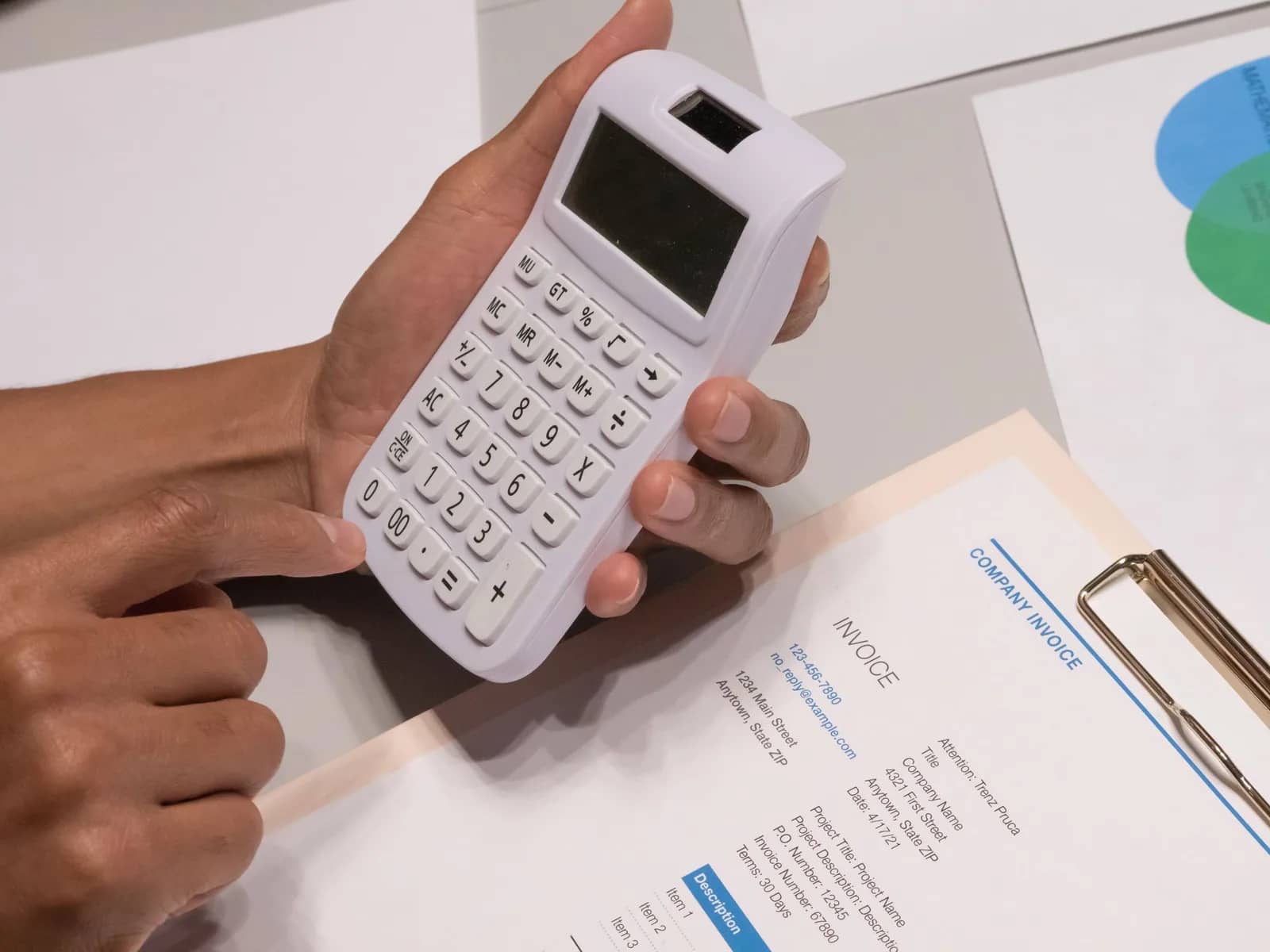 Contribuyente calculando el monto de una multa del SRI con facturas y calculadora sobre el escritorio