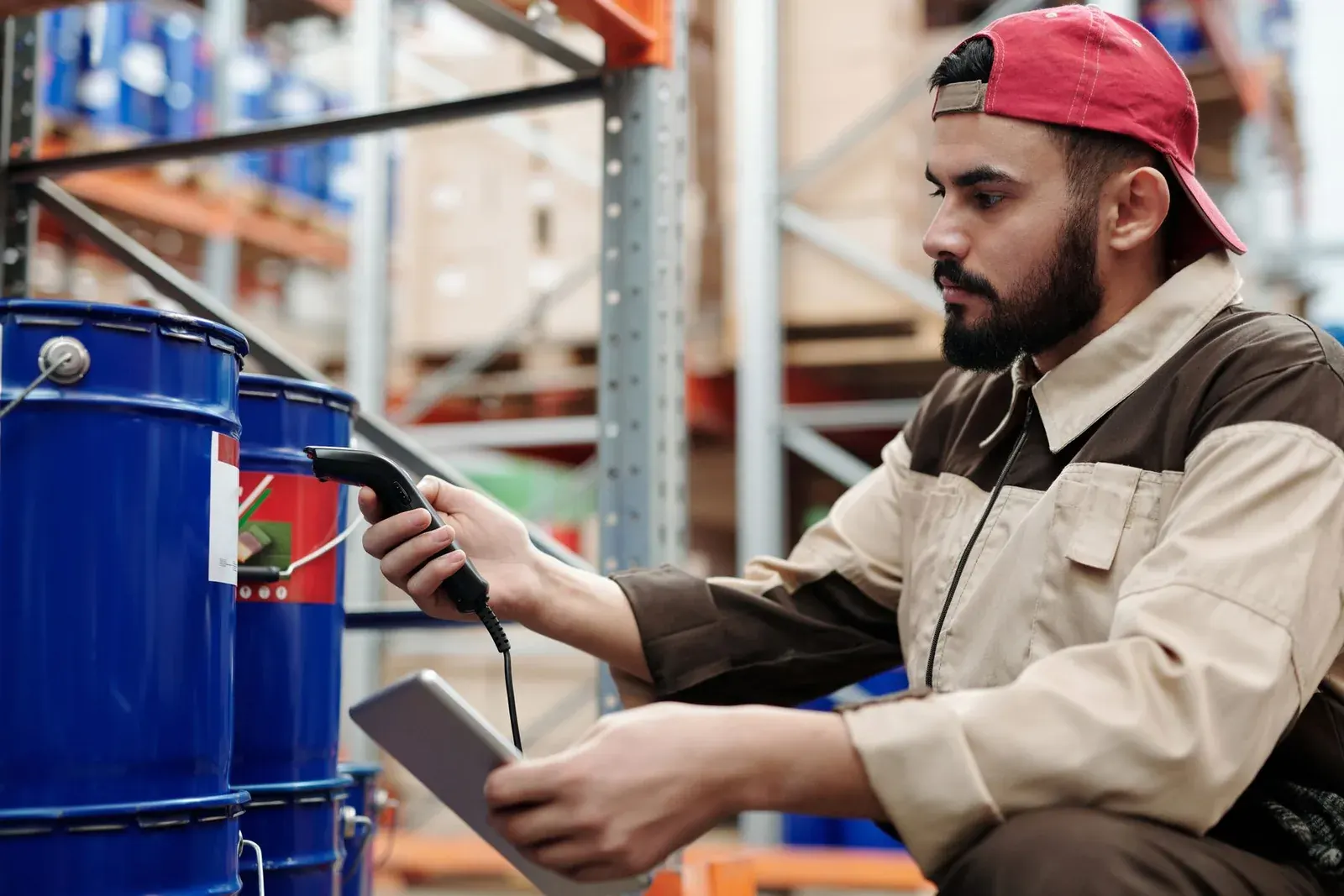 Trabajador de una bodega de distribución registrando productos con una tablet y un escáner de códigos de barras